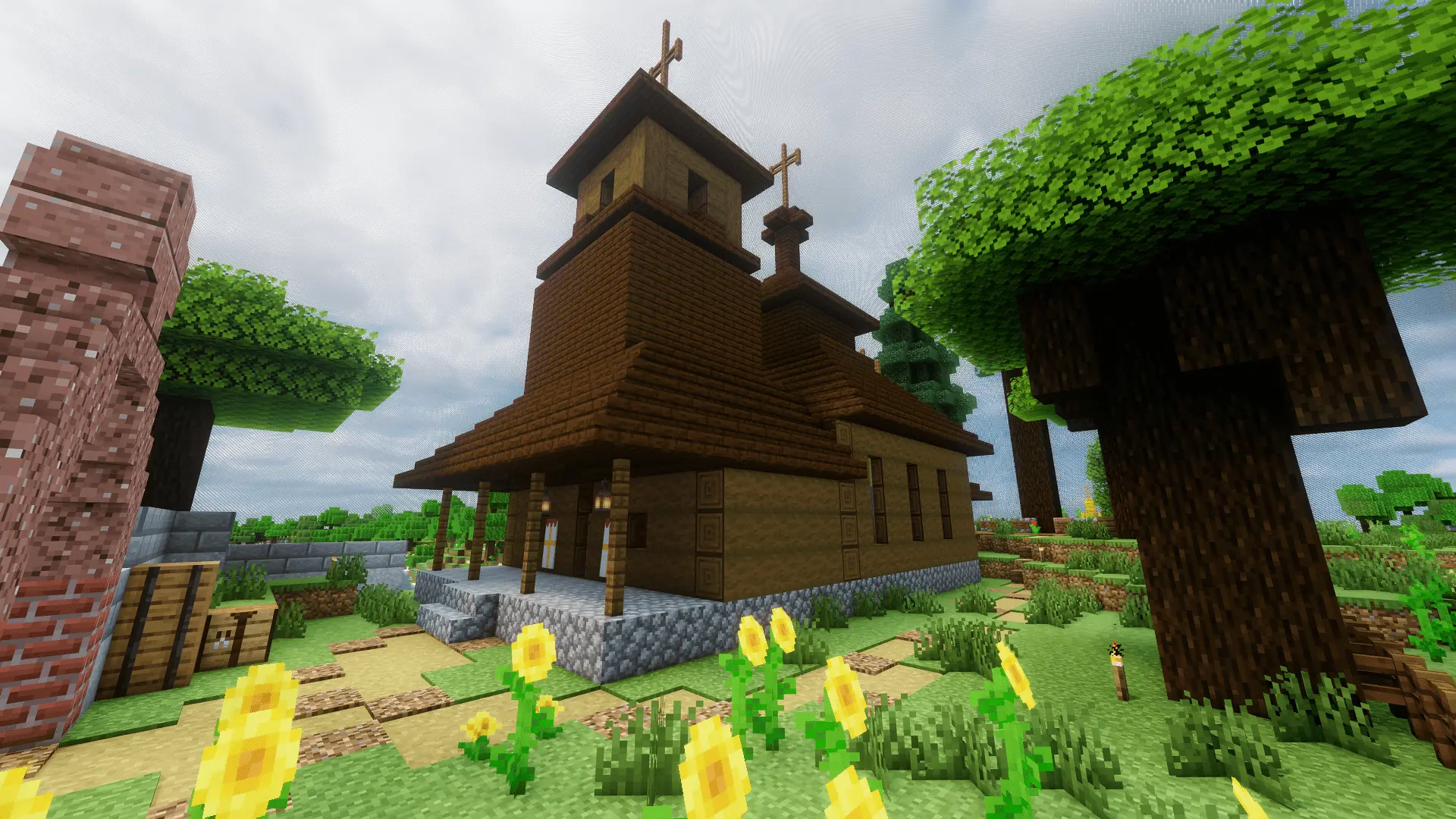 The wooden village church as seen from the outside. A bell tower sticks out the front part, and two wooden crosses decorate the roof