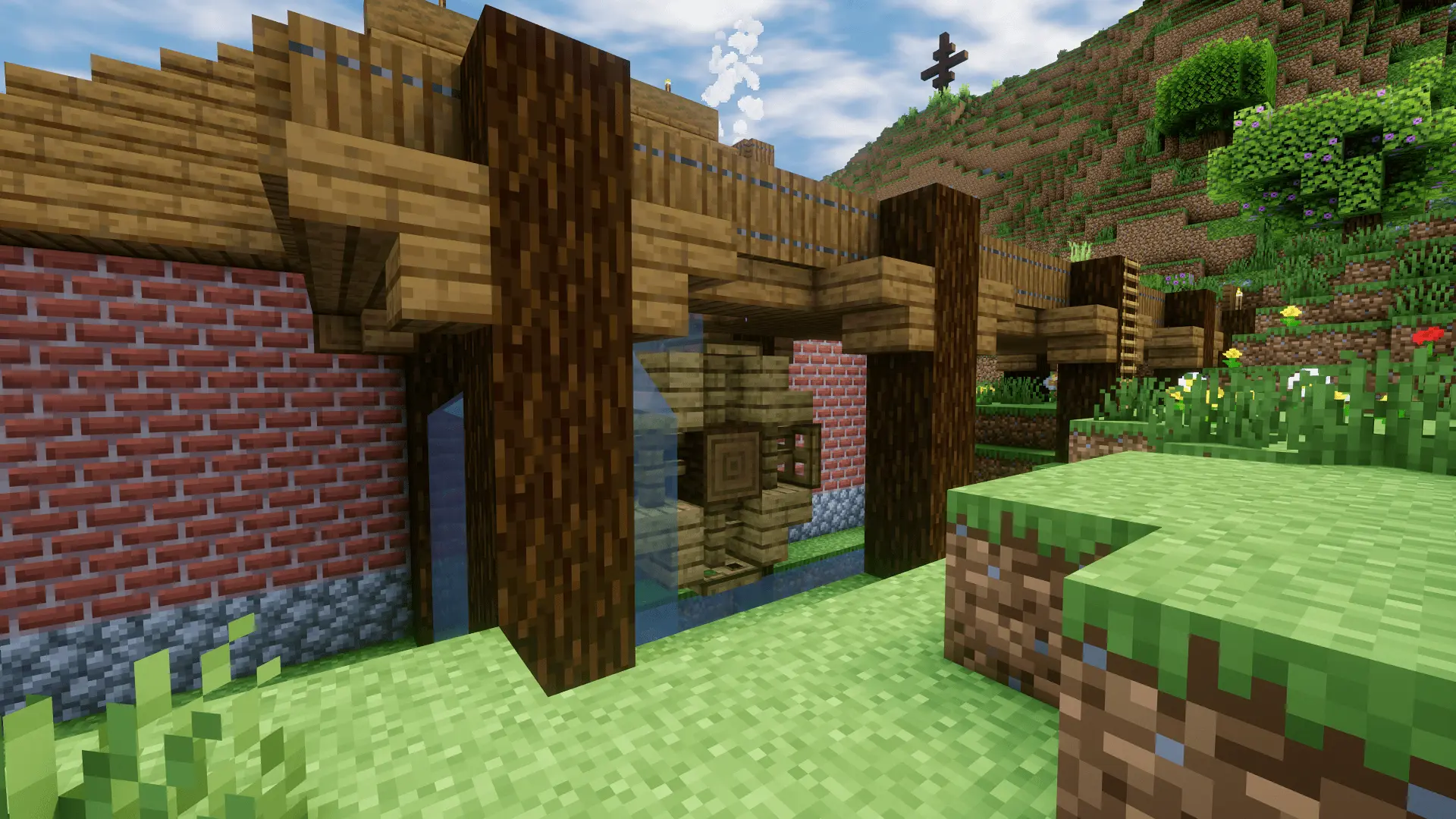 A close up of the water mill. The stream runs elevated through the wooden gutter, then drops onto a wheel, setting it in motion